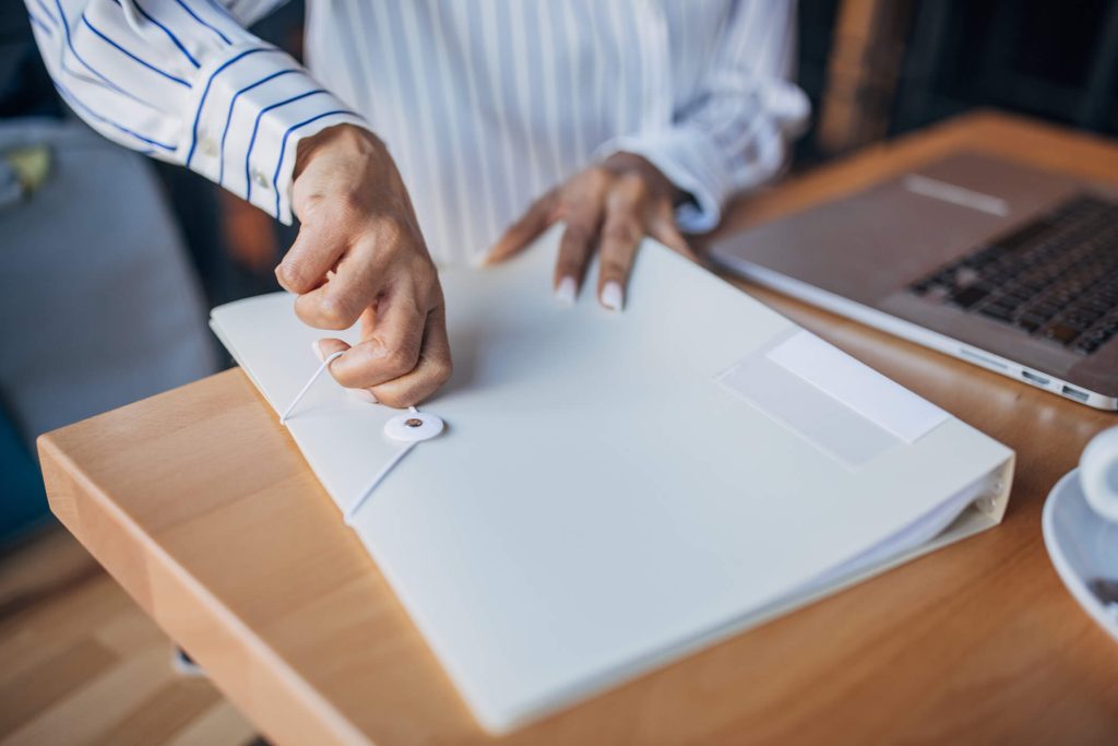 Person in doubt closes a folder with documents.