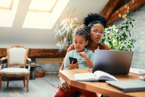 Parent reviewing family court documents online while balancing childcare responsibilities at home.