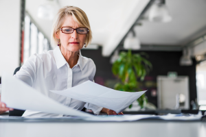 Woman reviewing important legal documents at her desk in an office.